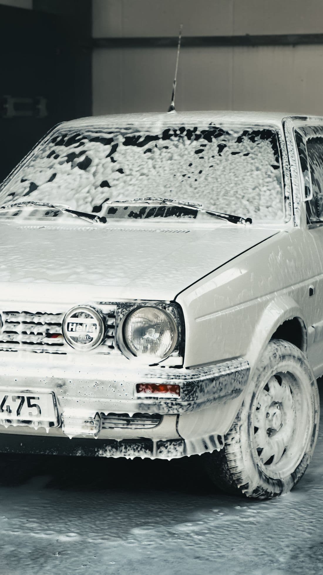 Classic car covered in soap foam at an indoor car wash facility