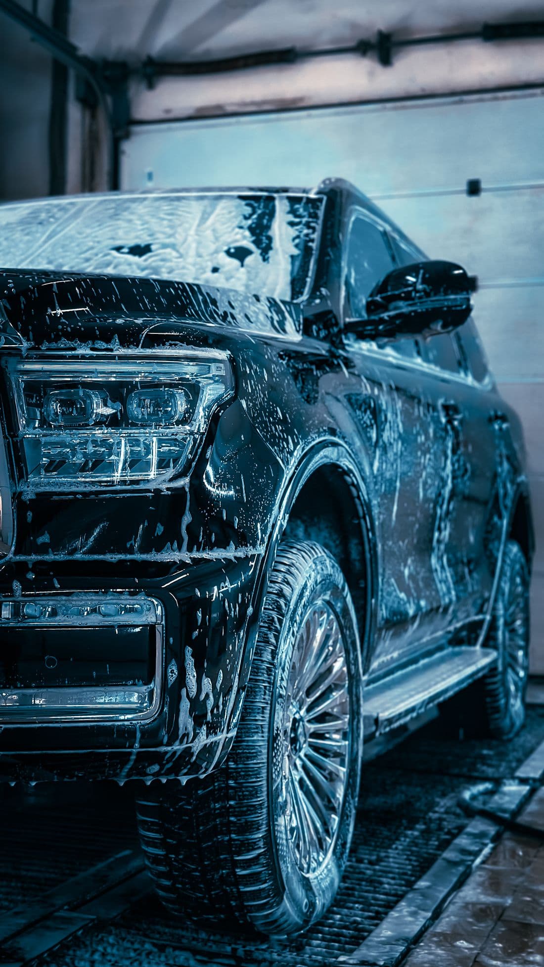 Black SUV covered in soap suds during an express car wash