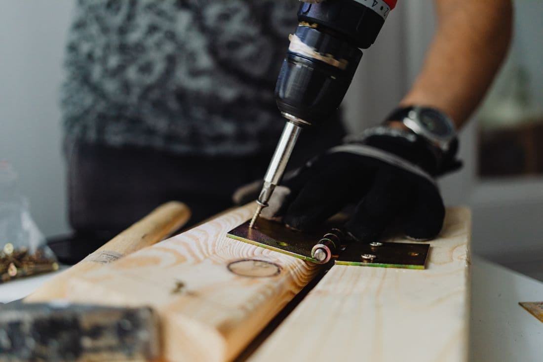 Handyman using a power drill on a wooden plank indoors