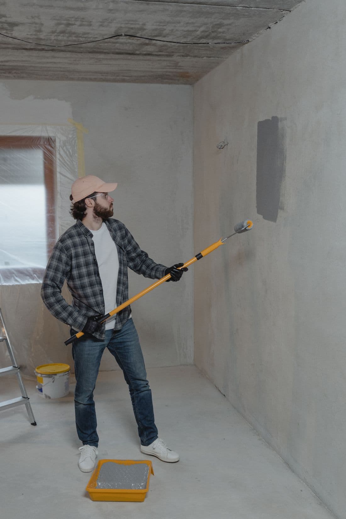 Close-up of a paint roller applying white paint to a textured interior wall