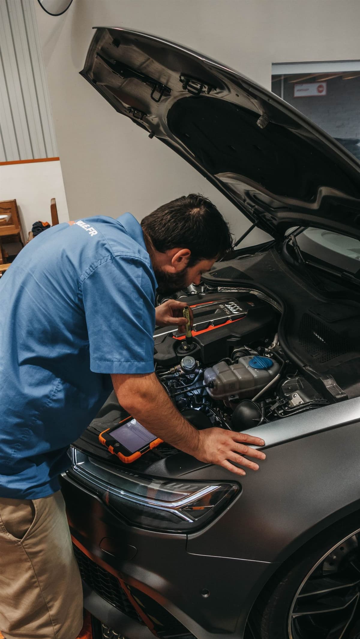 Mechanic working under a raised car with an inspection light in a repair shop