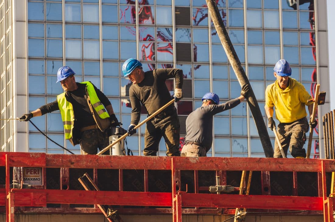 Construction workers in safety gear actively working on a high-rise building site