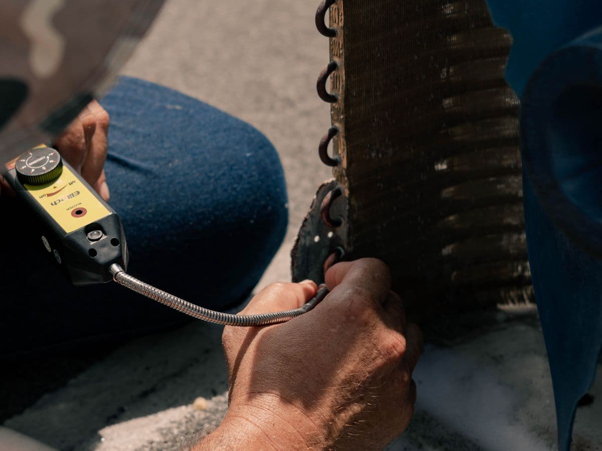 HVAC technician repairing an air conditioner unit with tools