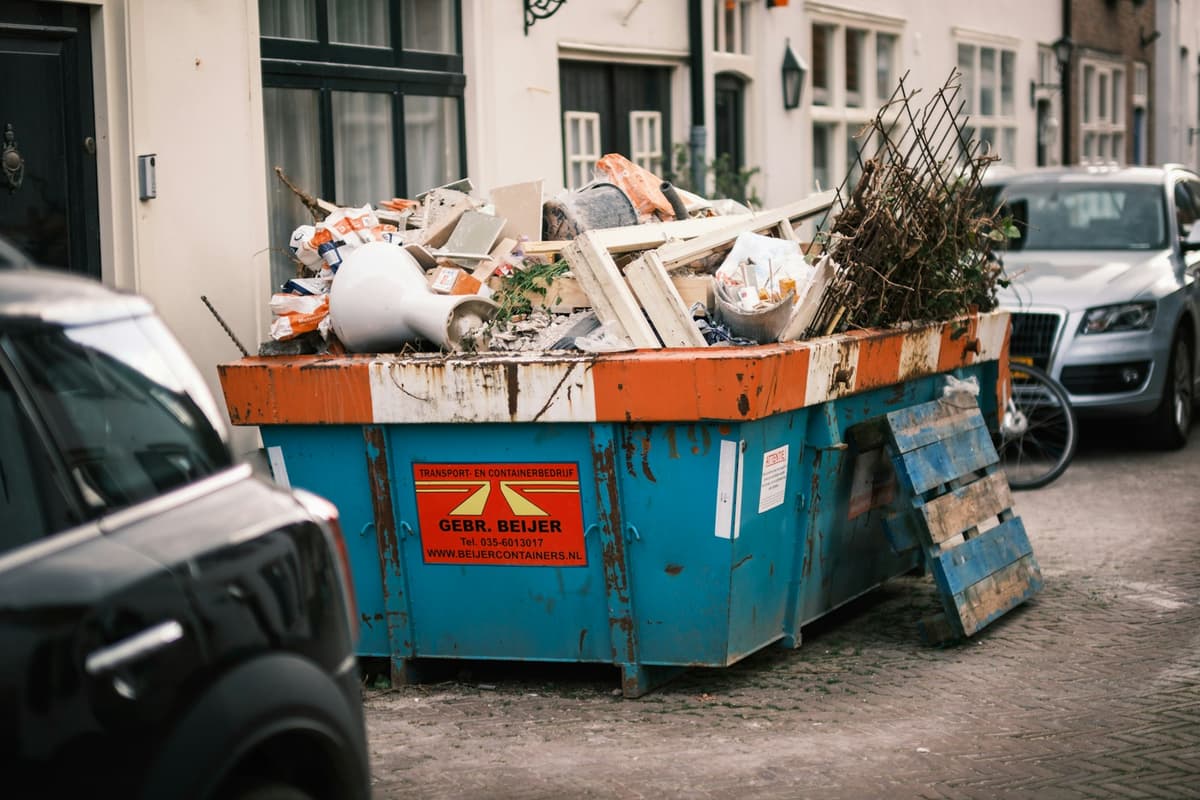 Worker sorting and loading scrap onto a junk collector truck on a city street