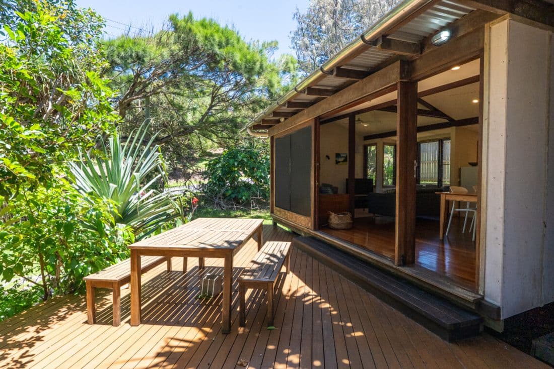 Modern wooden deck patio with outdoor dining furniture attached to a home