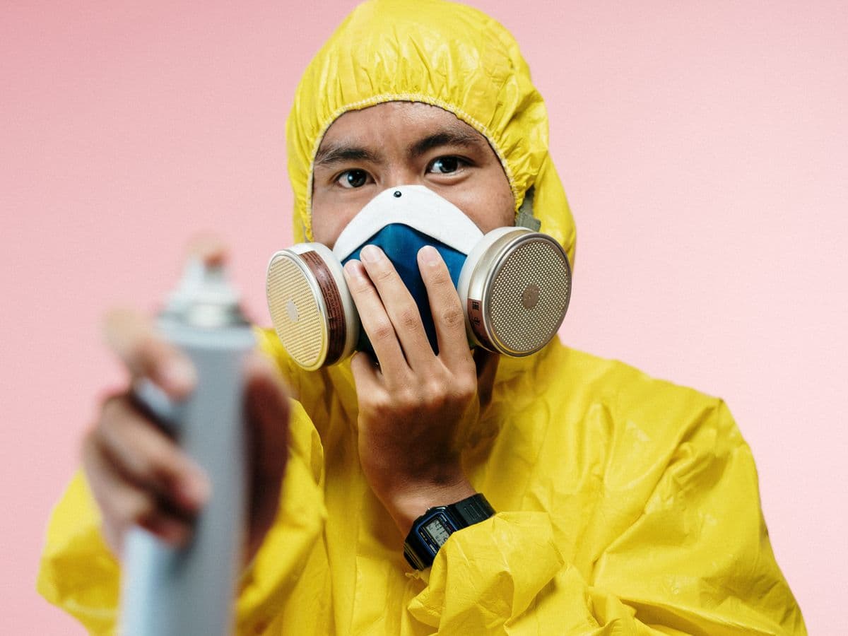 Pest control technician in protective gear with spray equipment