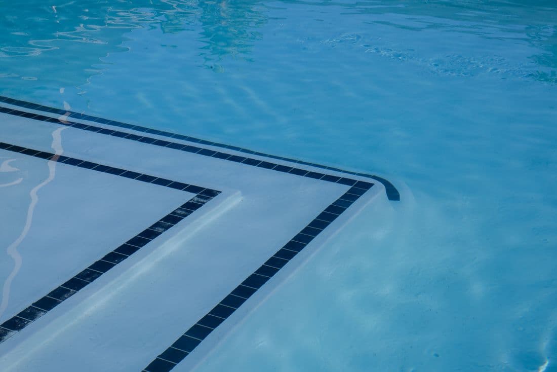 Clean blue swimming pool with tiled steps and shimmering water