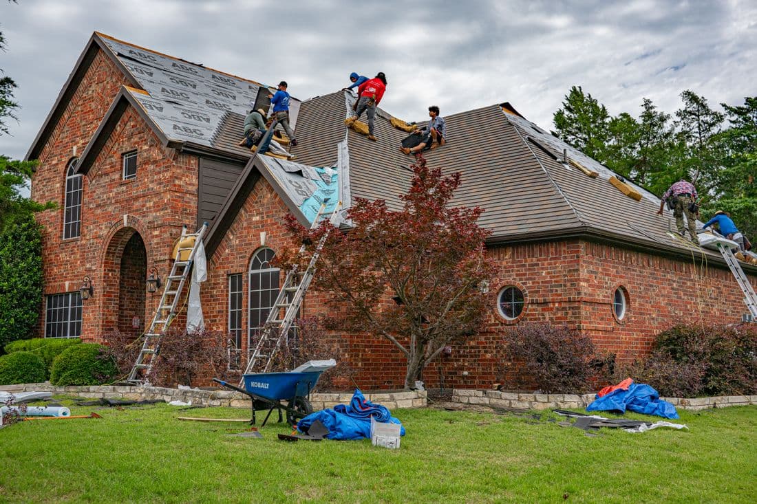Roofers working on shingle installation on a brick home in Texas