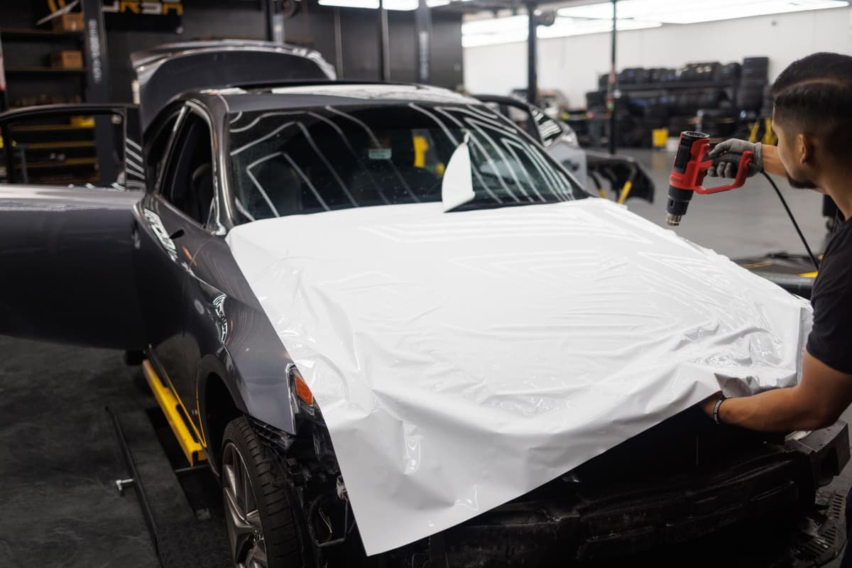 Technician applying window tint film to a vehicle in a shop